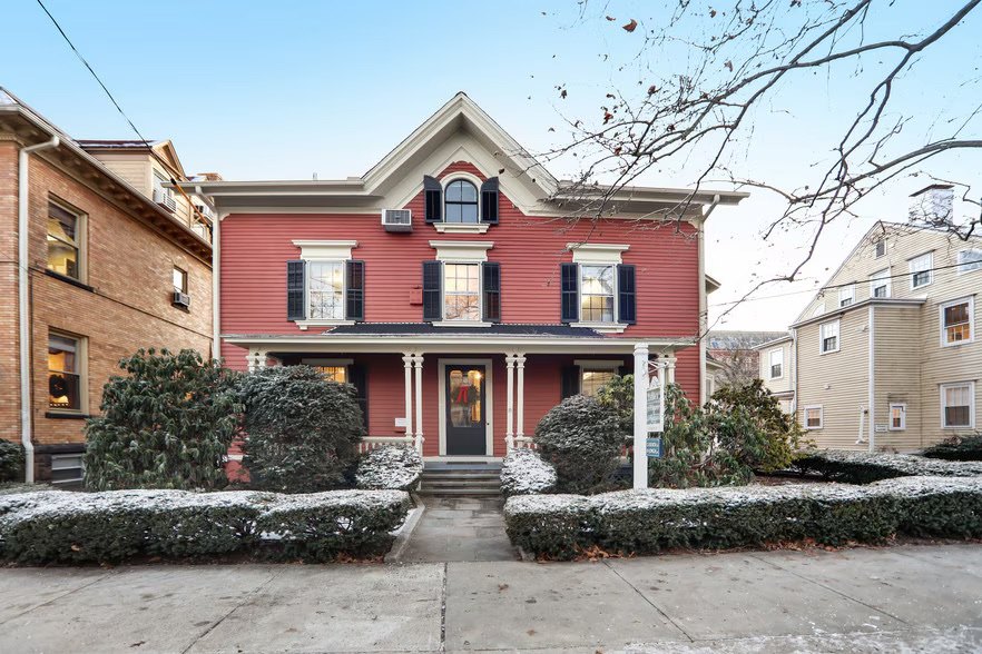 The New Haven house, a red Victorian, under snow.